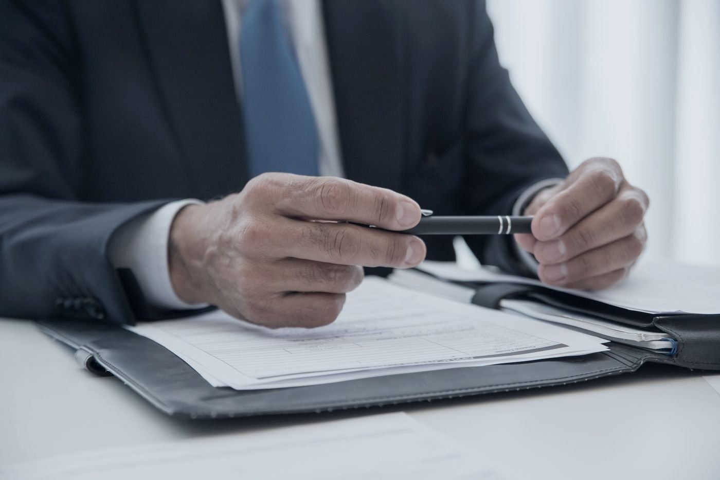 Profissional revisando documento técnico com caneta na mão